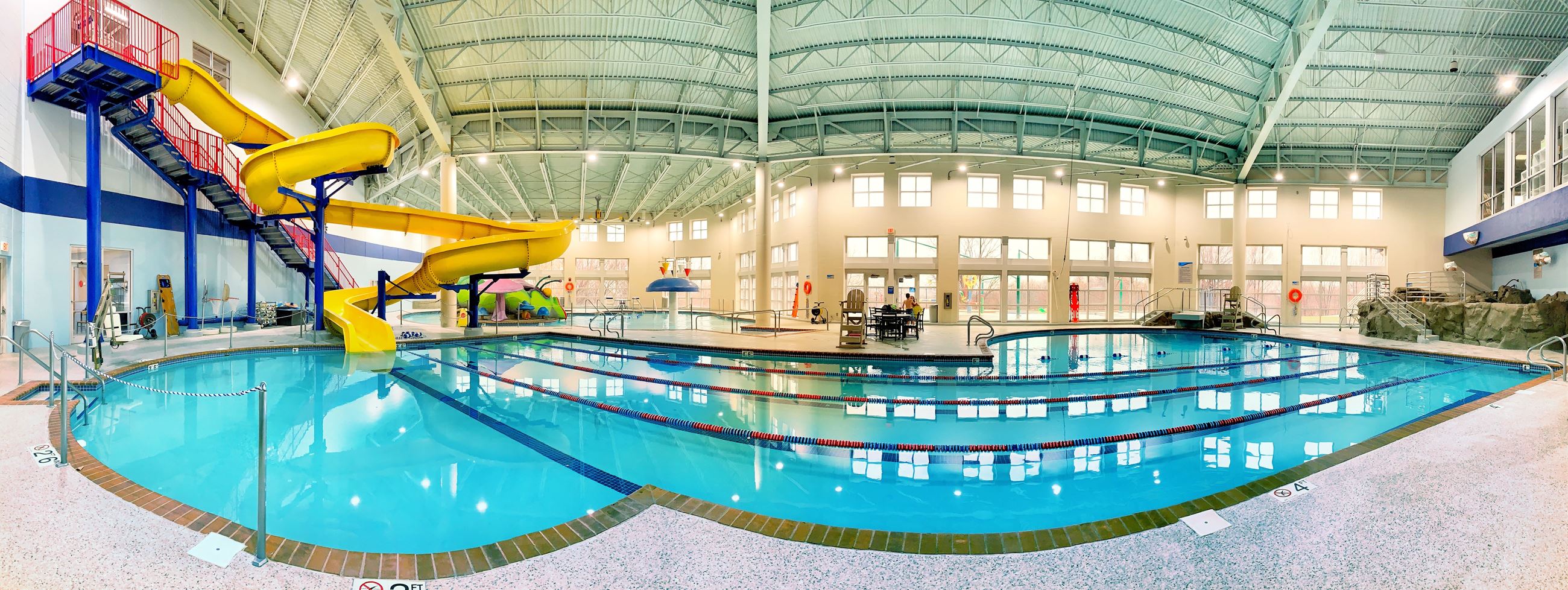 Fish eye view of the Chaska Community Center pool, featuring yellow slide, lap lanes, and deep end 